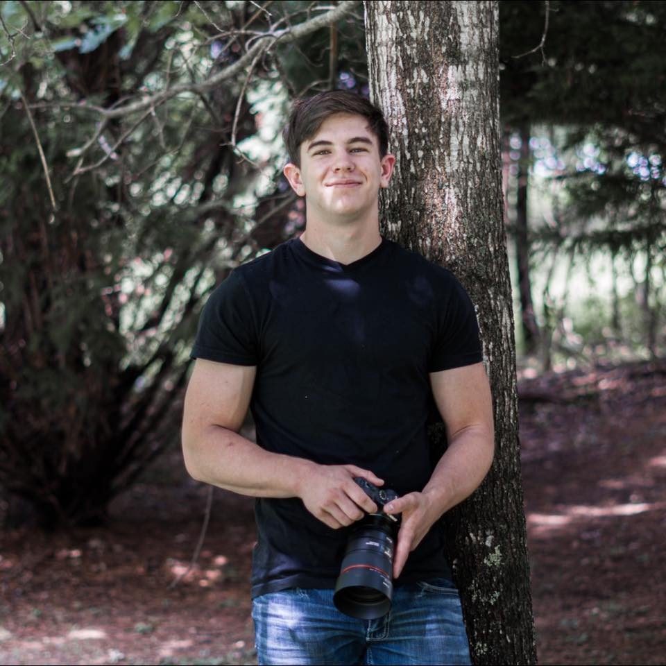 Kaleb Ledford, Blue Ridge Georgia photographer, holding a camera in the woods